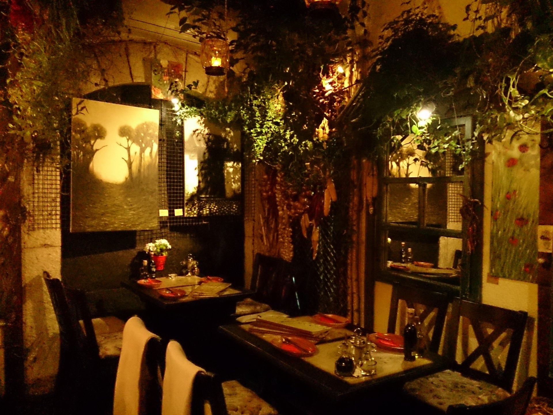 The candlelit dining room of Dveri, hung with plants and dried peppers