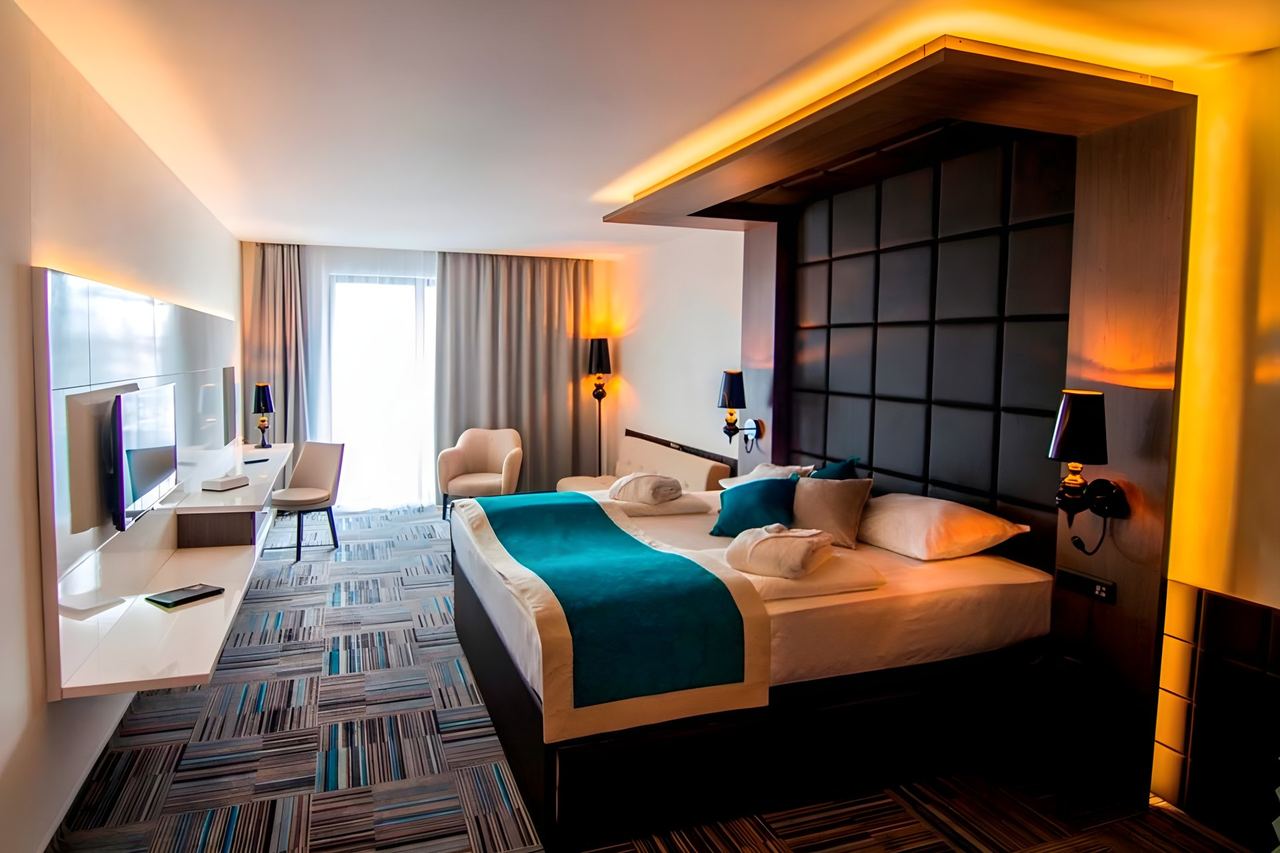 A room at Hotel Hills Sarajevo with a padded headboard and teal throw